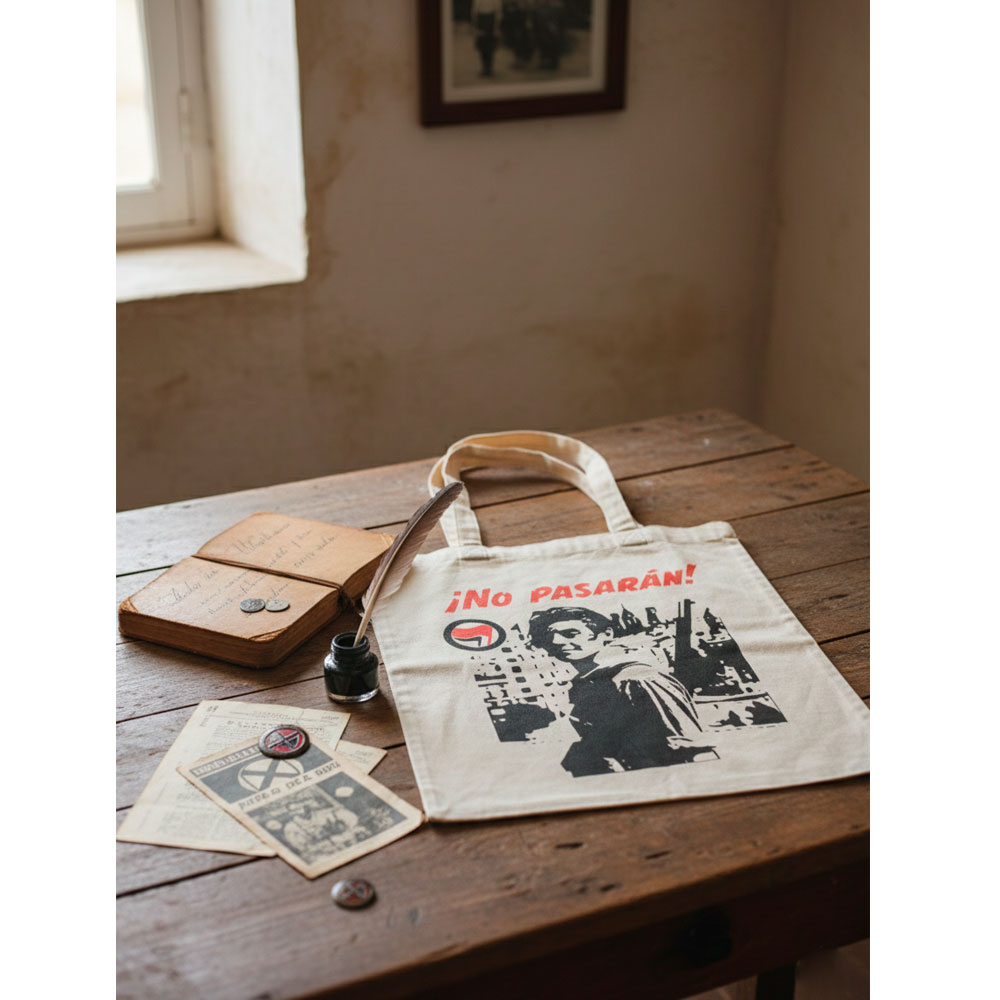 Tote bag No Pasarán de Ouh Rebel en una mesa de madera con estética vintage y tintero.