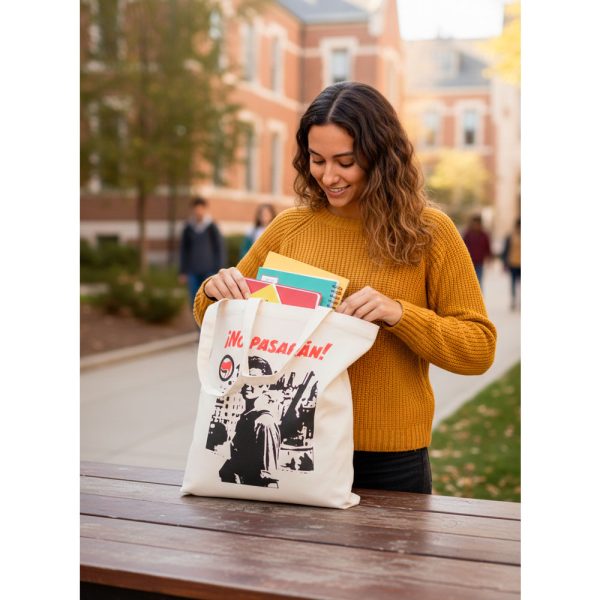 Mujer joven utilizando la tote bag No Pasarán para llevar libros y material de estudio.