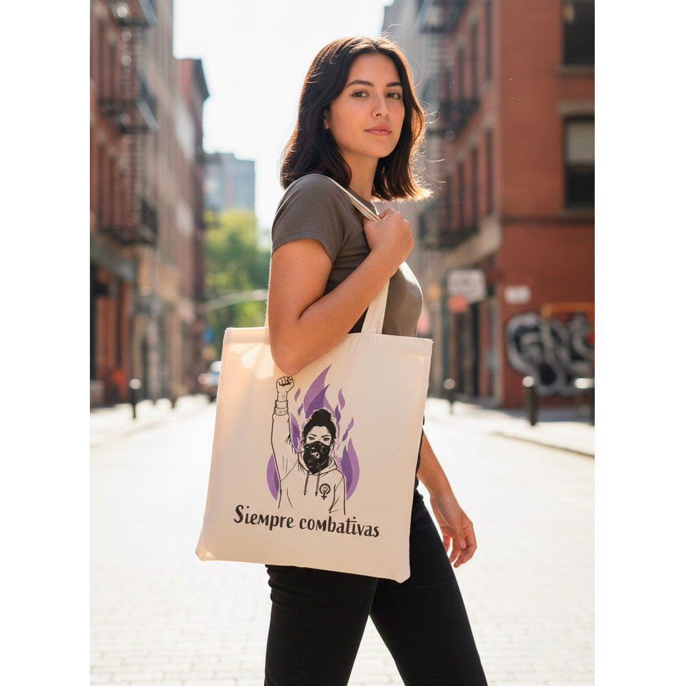 Mujer con estilo alternativo llevando la tote bag Siempre Combativas de color crudo.
