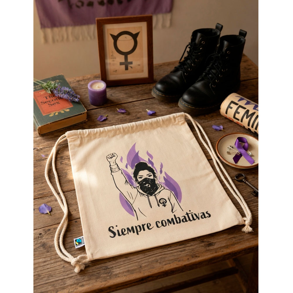 Mochila cruda Siempre Combativas de Ouh Rebel sobre madera junto a flores rojas y un libro de pensamiento crítico.