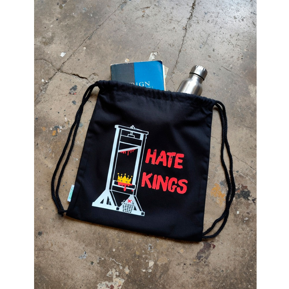Mochila Hate Kings de Ouh Rebel abierta sobre suelo de hormigón, mostrando un cuaderno y una botella metálica en su interior.