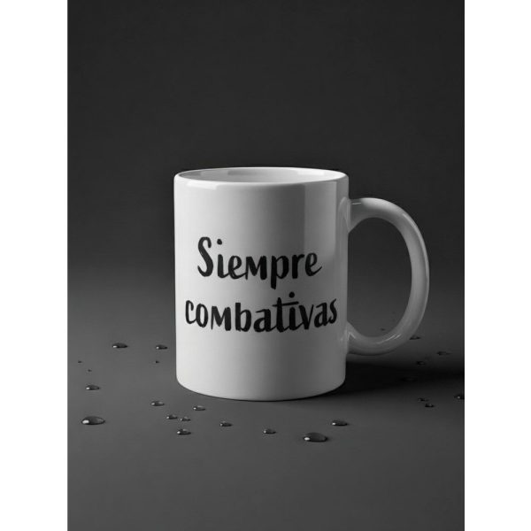 Taza blanca Ouh Rebel con la frase Siempre Combativas en caligrafía negra sobre fondo oscuro con gotas de agua