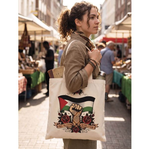 Chica de perfil caminando por un mercado al aire libre llevando al hombro el Tote Bag Free Palestine Revolution con un libro y una botella asomando.